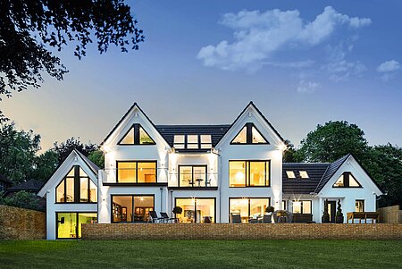 Haus mit großer Fensterfront in Abendstimmung