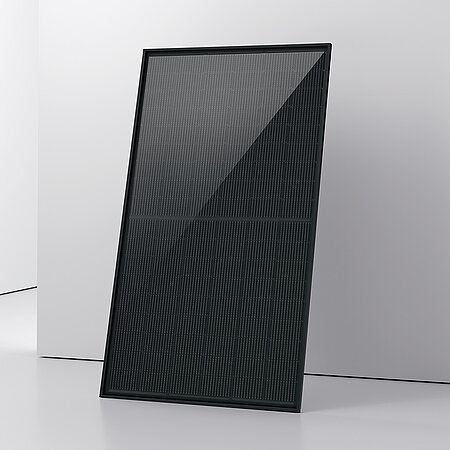 Ein aufrecht stehendes schwarzes PV-Modul mit einem strukturierten, glänzenden Oberflächenfinish. Es steht in einem hellen Raum mit glatten Wänden und einem weißen Boden. 