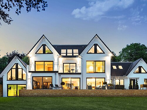 Haus mit großer Fensterfront in Abendstimmung